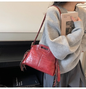 Detail of red crocodile texture leather bag with elegant side tassels and shoulder strap