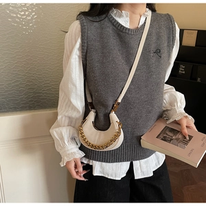Chic beige crescent bag with gold chain shown as part of a casual feminine outfit