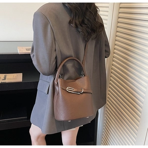 Detail of brown lychee grain leather bucket bag with silver metal buckles and shoulder strap