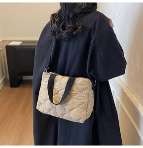Detail of beige quilted tote bag with black strap showing cross-body styling on a model