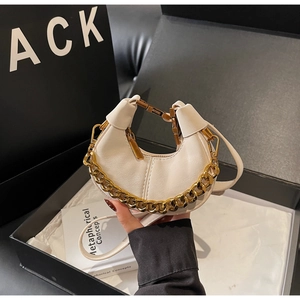 Detail of cream white leather crescent bag with chunky gold chain and zipper closure