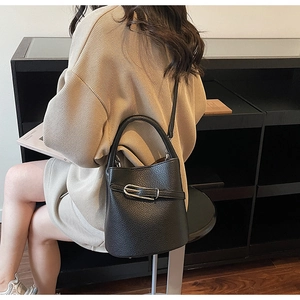 Detail of black pebbled leather bucket bag with silver buckle and versatile strap