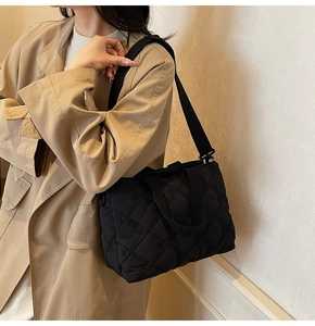 Detail view of black quilted tote bag with lattice stitching and long fabric shoulder strap