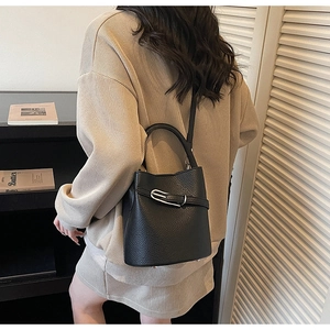 Detail view of black lychee grain leather bucket bag with silver buckle and handle