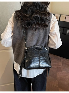 Fashionable black crocodile embossed shoulder bag with fringe tassel detail and metal eyelets
