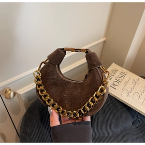 Détail du sac croissant en daim marron foncé avec une grosse chaîne en métal doré chic