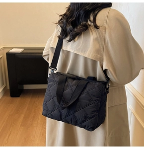Detail of black quilted shoulder bag with bow embroidery shown on a model