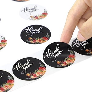 Florale Thank You stickers in zwart en wit die van de rol worden gehaald