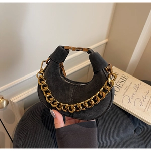 Detail of black suede crescent bag with chunky gold chain handle and metal clasp