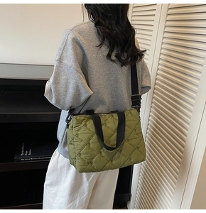 Detail of army green quilted tote bag with diamond pattern and wide woven shoulder strap