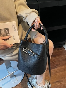 Minimalist black pebbled leather bucket bag with silver metal clasp and top handle