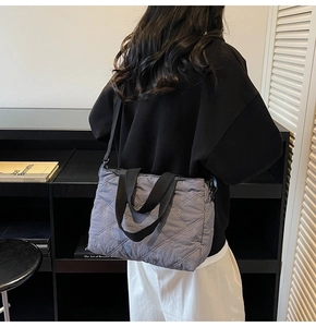 Detail of grey quilted tote bag with bow embroidery and black handles for daily use
