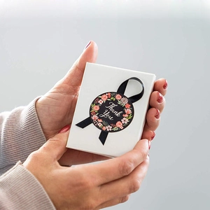 Square gift box with black ribbon and floral Thank You sticker held in hands
