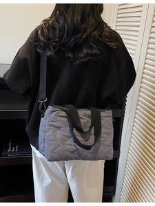 Quilted grey tote bag with diamond pattern and adjustable shoulder strap worn by model