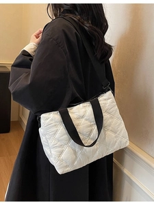 White quilted shoulder bag with floral embroidery and contrast black straps on model