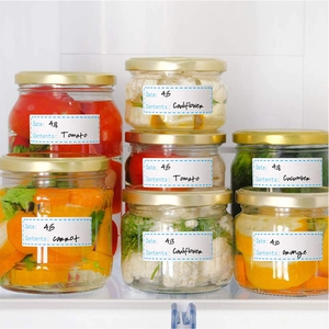 Detailed food storage stickers on glass jars showing date and contents in a fridge