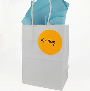 White gift bag with blue tissue paper featuring a round yellow sticker label for names