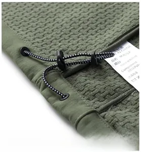 Close-up of olive fleece vest hem with adjustable drawstring and toggle closure