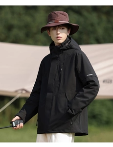 Detailansicht der schwarzen Outdoorjacke mit Reflektorstreifen und braunem Fischerhut
