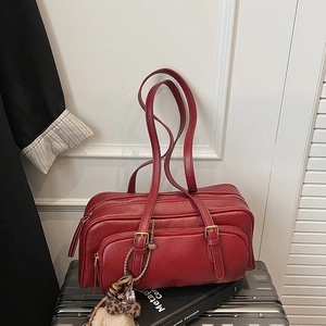 Detail of red vintage boston bag with golden hardware on a suitcase for travel setup