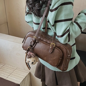 Detail of vintage brown shoulder bag with buckle straps and a cute plush dog pendant