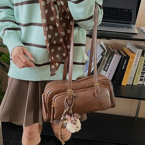Detail of vintage brown oil wax leather boston bag with plush bear charm on a shoulder strap