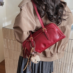 Red vintage underarm bag with zipper tassel and plush dog charm worn by a model