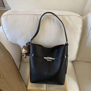 Close-up of black lychee leather bucket bag with silver metal buckle and monkey charm