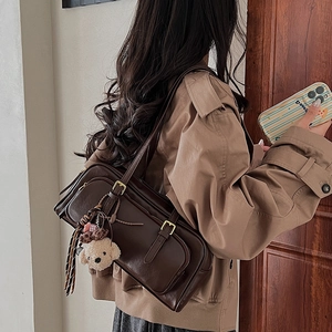 Detail view of deep brown vintage underarm bag with cute teddy bear charm on side