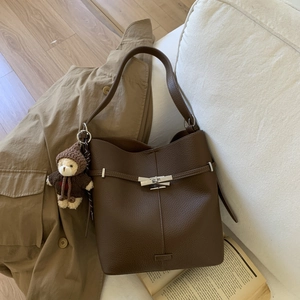 Detail of dark brown pebble leather bucket bag with silver buckle and plush bear charm