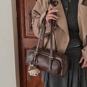 Macro view of vintage brown shoulder bag showing faux leather texture and metal buckles