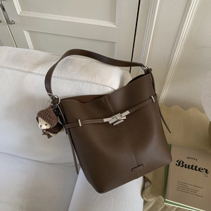 Detail of dark brown leather bucket bag with silver twist lock and cute bear charm