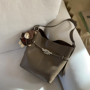Detail of a dark brown pebble leather bucket bag with silver clasp and bear charm