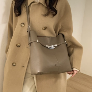Close-up of the silver metal swivel buckle and pebbled leather texture on the bucket bag
