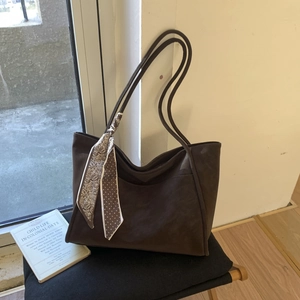 Close-up of dark brown tote bag featuring matte finish and decorative paisley silk scarf