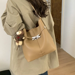 Detail of khaki leather bucket bag with silver metal buckle and cute bear pendant