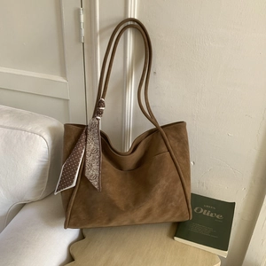 Macro detail of large brown suede tote bag with floral silk scarf decoration on handle
