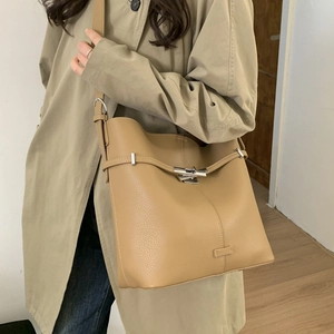 Detailed view of khaki pebbled leather bucket bag with metallic buckle and shoulder strap
