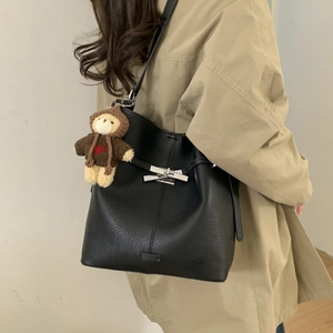 Detail of black pebbled leather bucket bag with silver buckle and cute teddy bear charm