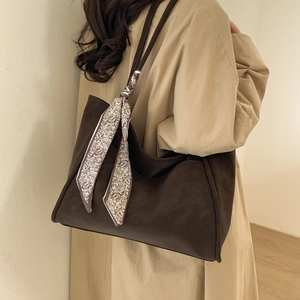 Detail of dark brown tote bag with decorative paisley scarf and matte leather texture