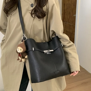 Detail of black pebbled leather bucket bag with silver lock and bear charm