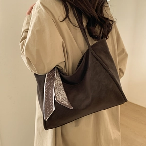 Close-up of deep brown leather tote bag with vintage patterned scarf on shoulder strap