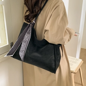 Detail of black tote bag with vintage patterned silk scarf tied on the strap