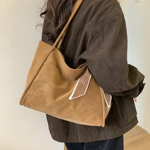 Detail of vintage caramel brown tote bag with silk scarf on a stylish model