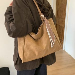 Detailed view of the large brown suede tote bag with a polka dot scarf accessory
