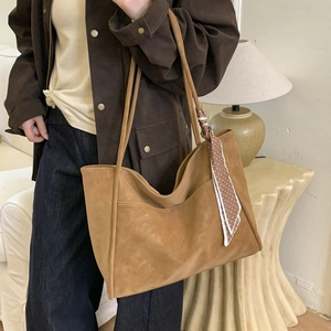 Detail of tan tote bag with soft suede texture and stylish polka dot silk scarf on handle