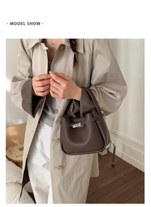 Deep brown bucket bag in litchi grain leather with silver lock shown on a model