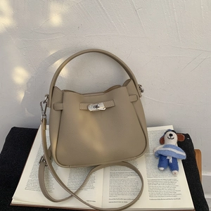 Macro detail of beige pebble leather bucket bag with metal buckle and dog charm
