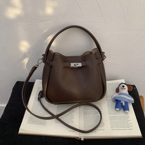 Macro shot of dark brown lychee leather bucket bag featuring silver lock and strap
