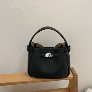 Detail of black lychee leather bucket bag with silver metal twist lock on wooden display